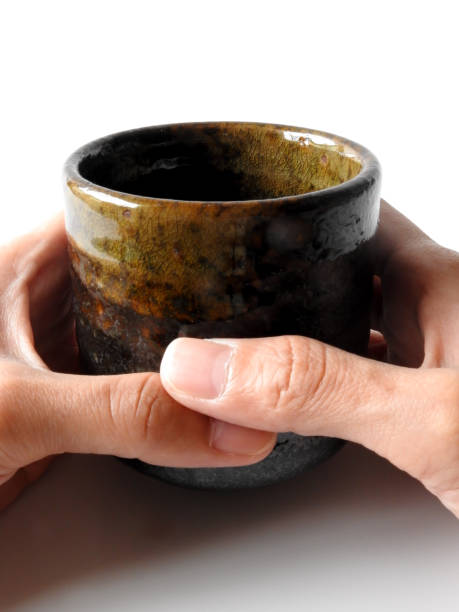 istock Pick up a dark brown pottery cup in one hand isolated on white background. 1316954336