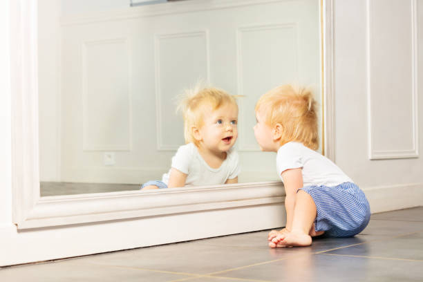 istock Little toddler boy play with big mirror on wall 1316956251