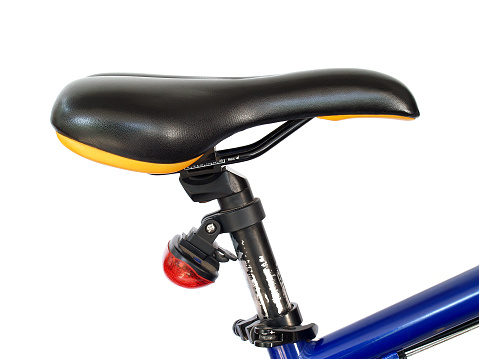 close up side of black leather bicycle seat with red taillight on old bicycle frame isolated on white background