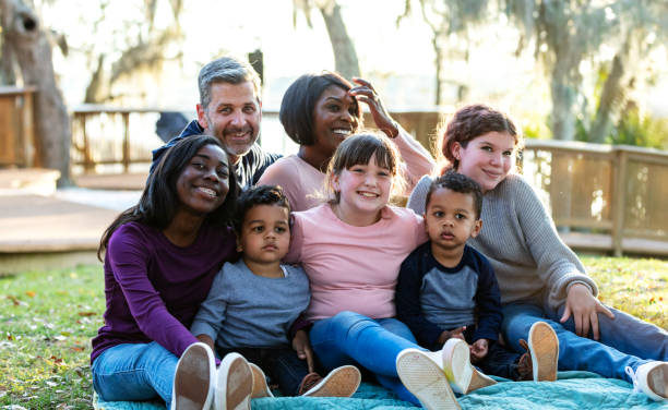 istock Blended family with five children sitting in park 1316963371