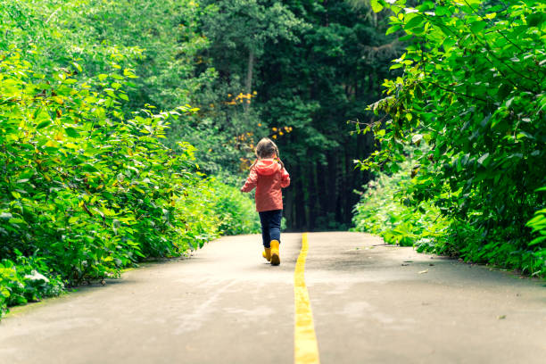 istock a child in yellow boots runs along the path in the park 1316974171