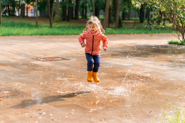 istock child jumping and playing in a puddle after rain 1316974259