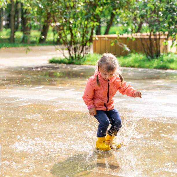 istock child jumping and playing in a puddle after rain 1316974262
