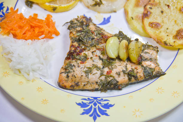 Beautifully cooked salmon with oranges around and dills, parsley, garlic and stuffing inside the fish