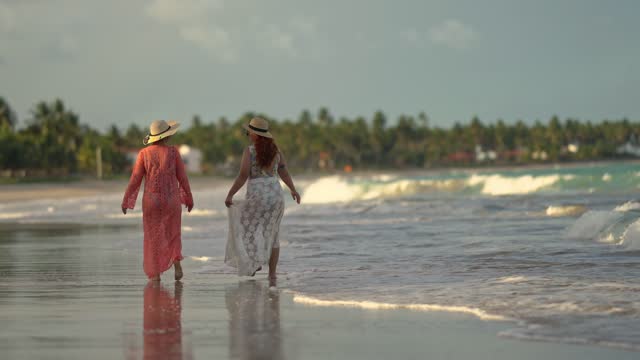 Rear view of mother and daughter walking on the beach