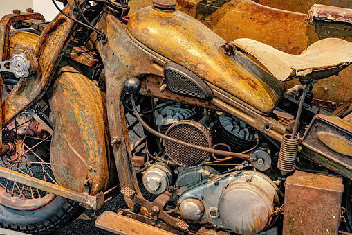Vintage weathered English motorcycle in front of a black background