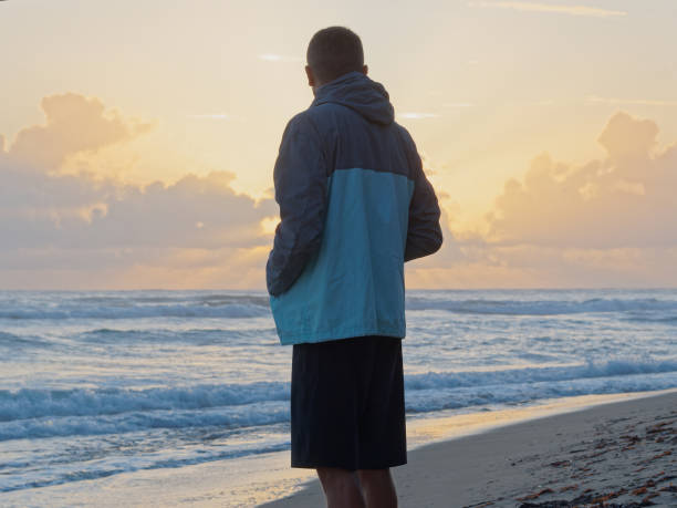 istock Thoughtful man standing watching the sunrise on tropical beach. Back view. 1316989943