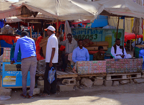 Hargeisa, Somaliland, Somalia: money changers and their customers - downtown street stall with large stacks of money (Somaliland Shillings bank notes, the currency is pegged to the United States dollar) - al fresco currency exchange dealers.