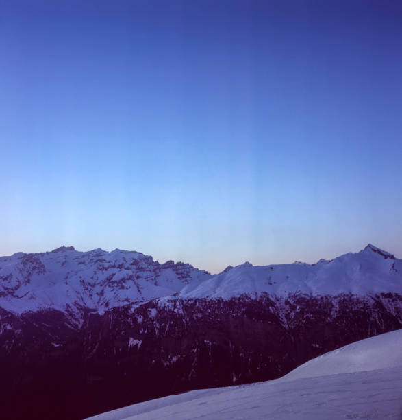 The sunset in winter during a wind storm with the snow being blown away on a peak near Lenzerheide in Switzerland shot with analogue film technique The sunset in winter during a wind storm with the snow being blown away on a peak near Lenzerheide in Switzerland shot with analogue film technique arosa stock pictures, royalty-free photos & images