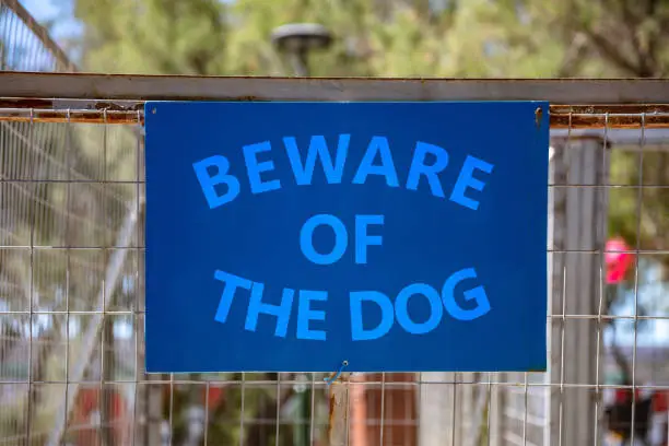 Beware of the dog, Warning messagel, text on blue sign. Label on metal rusty wire mesh fence background inform about caution, danger canine attack, attention.