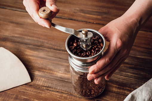 Moler granos de café en una trituradora de café manual sobre una mesa de madera. Copiar espacio photo