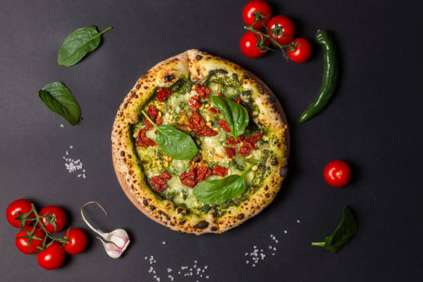 istock Pizza margherita bianca with mozzarella, dried tomatoes, pesto and pine nuts. Overhead, black background 1316998876