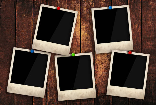 Empty instant photo frames pinned on wooden wall