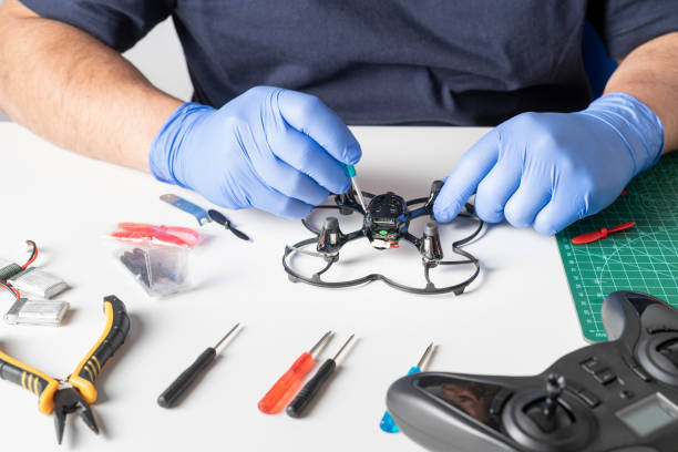 istock Man disassembling a toy drone with a screwdriver. Various tools and spare parts of the drone on a table. View of the hands repairing 1317001475
