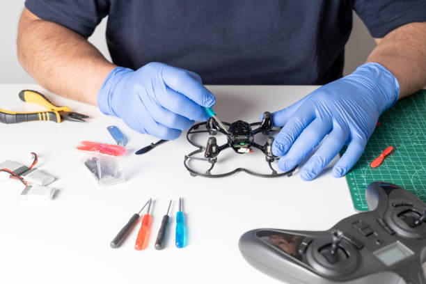 istock Man disassembling a toy drone with a screwdriver. Various tools and spare parts of the drone on a table. View of the hands repairing 1317001492