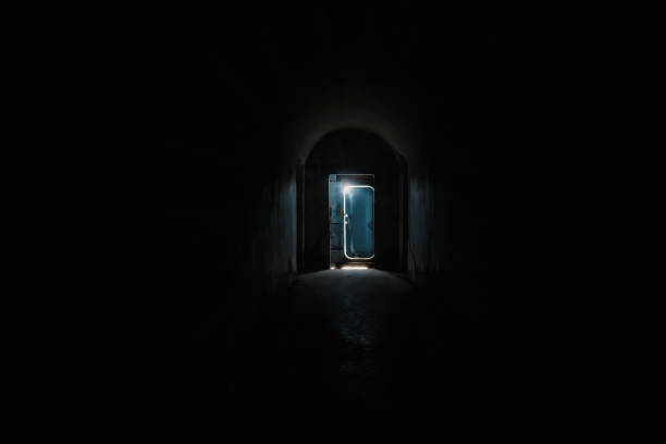 Dark tunnel and the door  silhouette with a light behind it at the end.