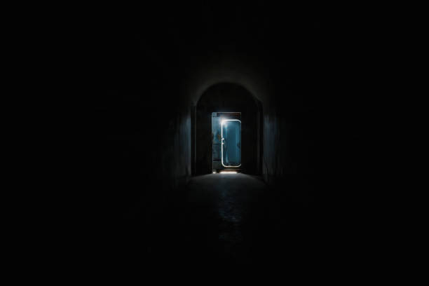 Dark tunnel and the door  silhouette with a light behind it at the end. stock photo