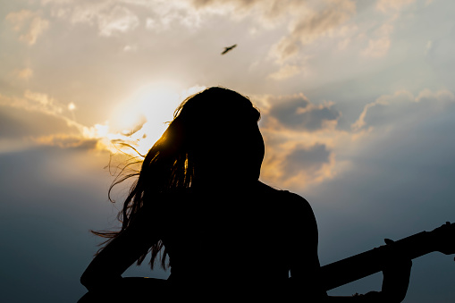 A silhouette of woman with guitar in backlight