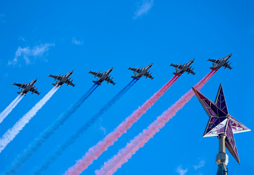 MOSCOW, RUSSIA - MAY 7, 2021: Avia parade in Moscow. Group of Russian fighters Sukhoi Su-25 with painted russian flag in the sky on parade of Victory in World War II in Moscow, Russia