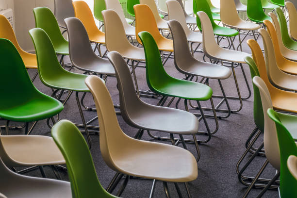 rows of seats in assembly hall. colored plastic chairs on gray floor. school assembly room. - school hall imagens e fotografias de stock