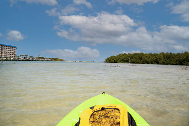 le soleil brille à travers les nuages au-dessus d’un kayak vert dans l’eau du nouveau col - bonita springs photos et images de collection