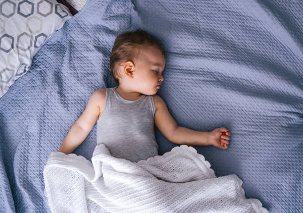 Cute baby girl sleeping on bed. Female toddler is with blanket is relaxing at home. She is in bedroom.