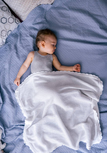Toddler girl sleeping on bed at home
