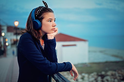 Nostalgic teenage girl is listening to music on the beach