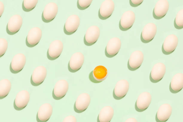 istock background of brown eggs with one broken in the middle on green background. 1317022530