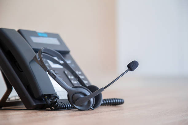istock Communication support, call center and customer service help desk. VOIP headset on telephone keyboard. 1317036201