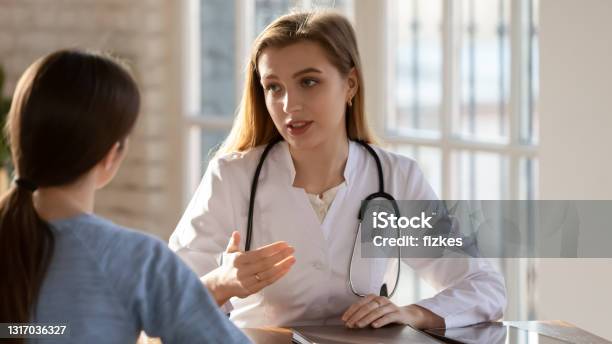 Focused Young Beautiful Female Doctor Talking With Patient Stock Photo - Download Image Now