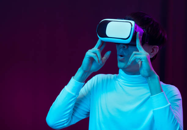 istock Excited asian young man wearing VR headset in neon light, Future technology concept 1317039562