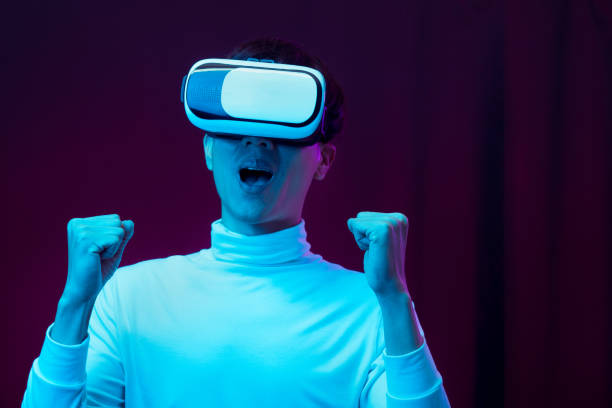 istock Excited asian young man wearing VR headset in neon light, Future technology concept 1317039588
