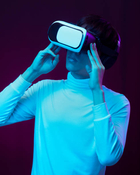 istock Young asian man wearing virtual reality goggles watching 360 degree video in neon light, Technology concept 1317039590