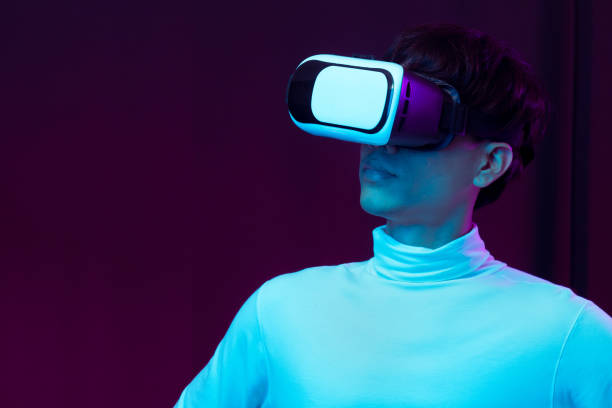 istock Young asian man wearing virtual reality goggles watching 360 degree video in neon light, Technology concept 1317039594