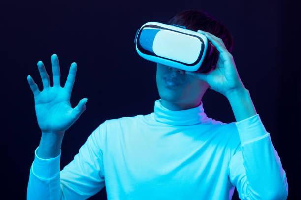 istock Young asian man wearing virtual reality goggles watching 360 degree video in neon light, Technology concept 1317039604