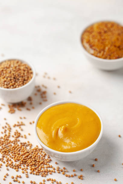 istock Mustard sauce in a bowl and seeds on a bright background. 1317042395