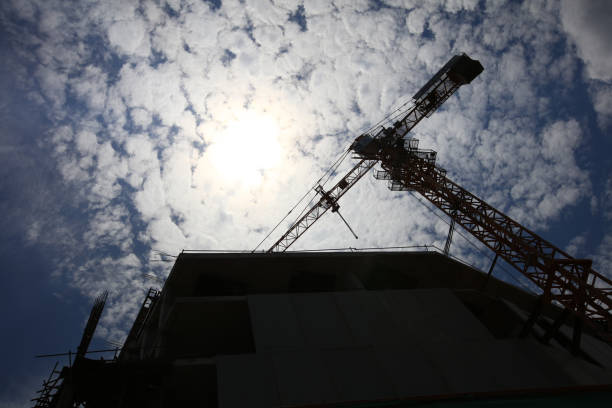 Button up view of construction power crane and new building under construction against sunshine on sunny day