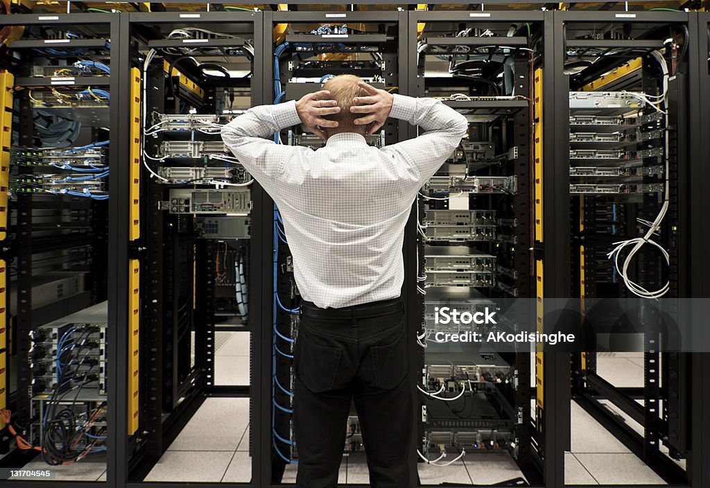 Trouble in data center Man looking astonished in a network data center. Crisis Stock Photo