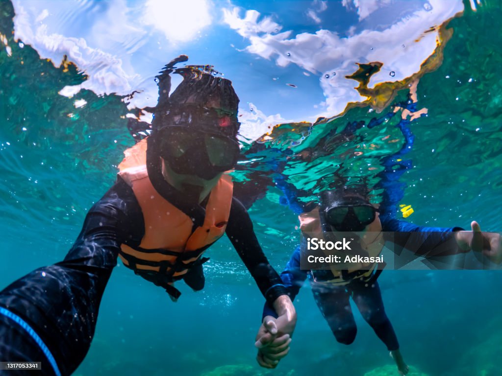 Happiness couple taking selfie under tropical sea Happiness couple taking selfie under tropical sea by water camera while excursion - Image Snorkel Stock Photo