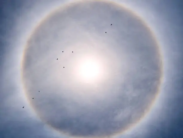 Halo around the sun on blue sky with white clouds in sunny day, natural phenomenon