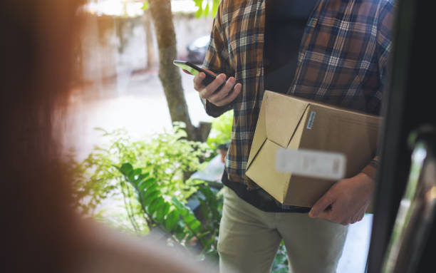 istock a delivery man with mobile phone holding parcel box to delivery 1317059946