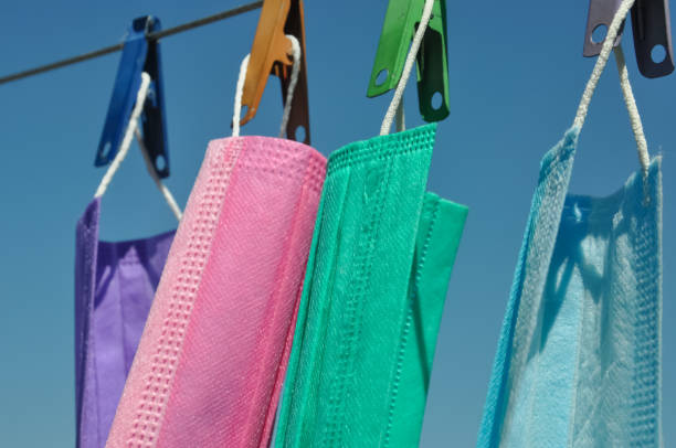 istock Side view of multi colored surgical face mask (Disposable mask) hanging on clothesline wire with clothespin, Concept of protect environment from waste and pollution. 1317064751
