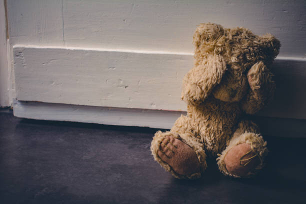 Abandoned Teddy Covering His Eyes, Sitting At A Door - Child Abuse Concept Abandoned Teddy Covering His Eyes, Sitting At Door - Child Abuse Concept child abuse photos stock pictures, royalty-free photos & images