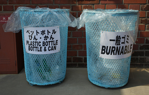 A Japanese street with garbage baskets for separating bottles, cans, and general trash