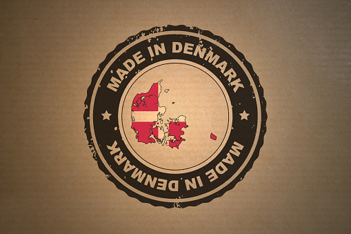 Brown paper with in its middle a retro style stamp Made in Denmark include the map and flag of Denmark.