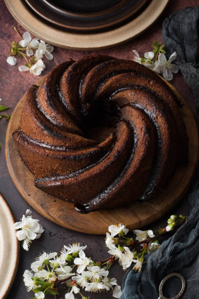 pastel bundt casero con flores sobre un fondo oscuro. - chocolate bundt cake fotografías e imágenes de stock