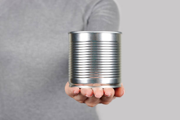 istock Hand with metal can, preserve tin on grey background 1317075157