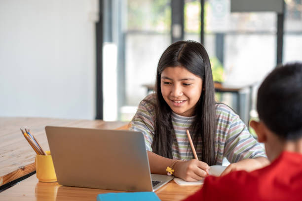 istock Young Asian girl happy online learning using laptop and taking notes in the classroom. 1317075829