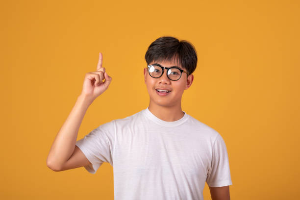 istock Young Asian man standing on orange background, pointing his finger. Looking at camera. 1317075880